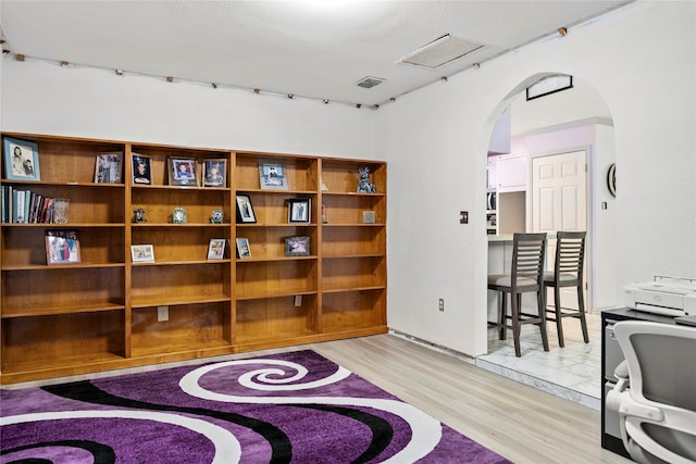 office space with arched walkways, visible vents, and light wood finished floors