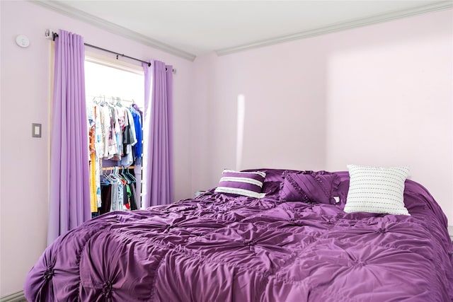 bedroom with a closet, a spacious closet, and crown molding