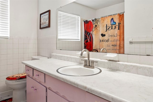 full bath with toilet, a wainscoted wall, tile walls, and vanity