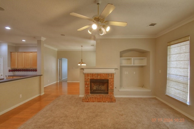 unfurnished living room featuring built in features, visible vents, ornamental molding, and a fireplace