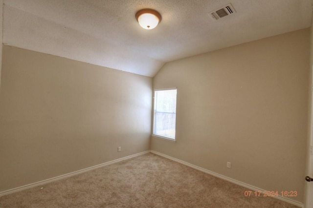 unfurnished room featuring vaulted ceiling, carpet, visible vents, and baseboards