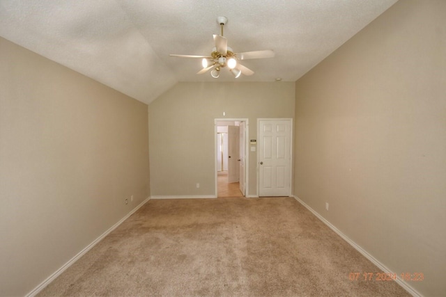 unfurnished bedroom with lofted ceiling, light colored carpet, ceiling fan, a textured ceiling, and baseboards