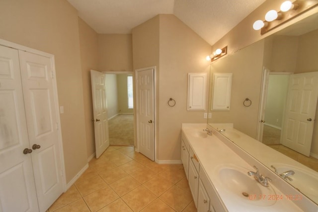 bathroom with vaulted ceiling, double vanity, tile patterned flooring, and a sink