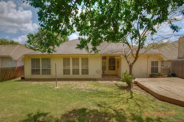 rear view of property with fence and a lawn