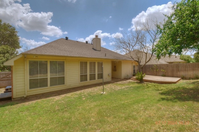 back of property featuring roof with shingles, a chimney, fence, and a yard