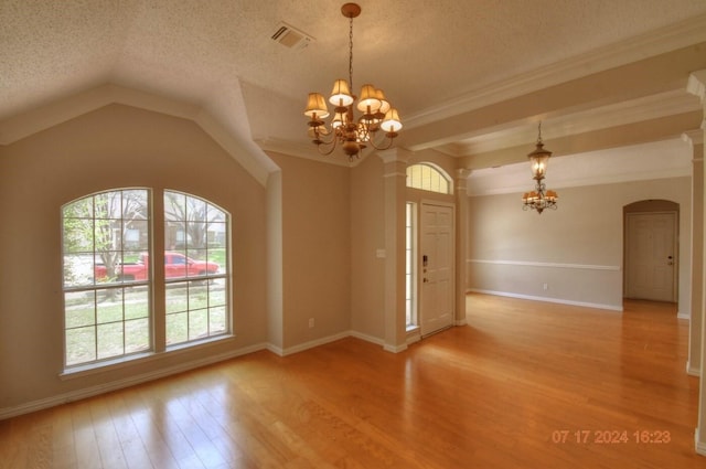 interior space with light wood-type flooring, a chandelier, arched walkways, and a textured ceiling