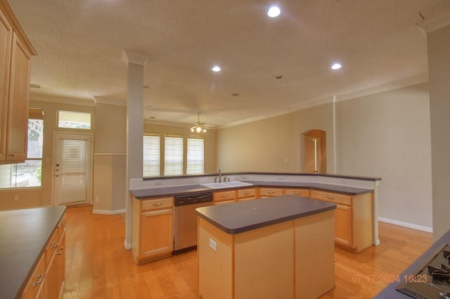 kitchen with dishwasher, dark countertops, light wood-style flooring, a kitchen island, and a sink