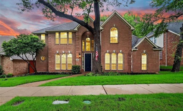 view of front of home with brick siding and a yard