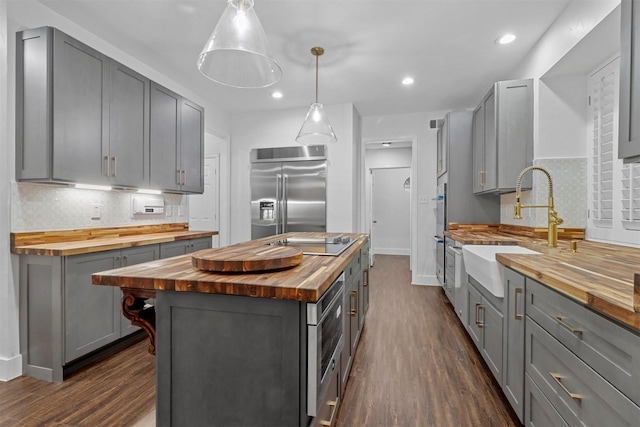 kitchen with a sink, wooden counters, stainless steel built in refrigerator, and gray cabinets