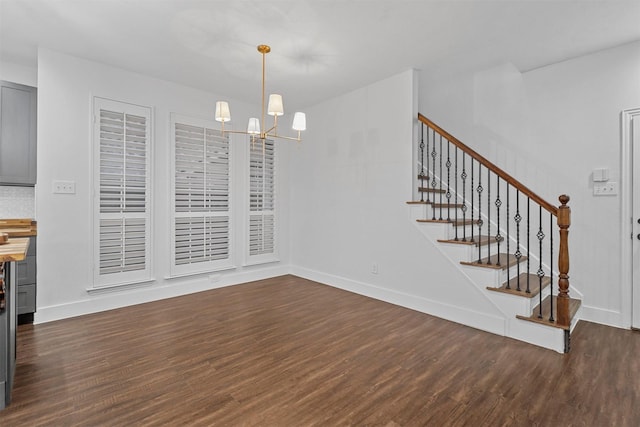 unfurnished dining area with stairs, dark wood-style flooring, baseboards, and an inviting chandelier