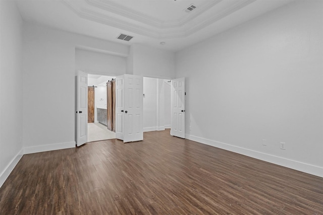 unfurnished bedroom featuring a raised ceiling, visible vents, dark wood finished floors, and baseboards