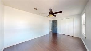 unfurnished bedroom featuring baseboards, visible vents, ceiling fan, dark wood-type flooring, and a closet