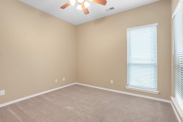 unfurnished room with light carpet, baseboards, visible vents, and a ceiling fan