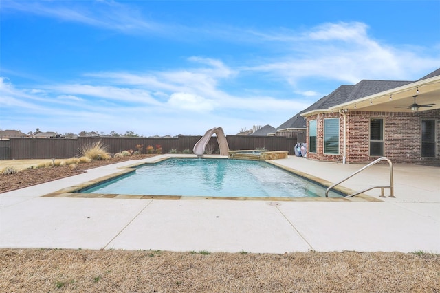 view of swimming pool with a patio, a water slide, a fenced backyard, an in ground hot tub, and a ceiling fan