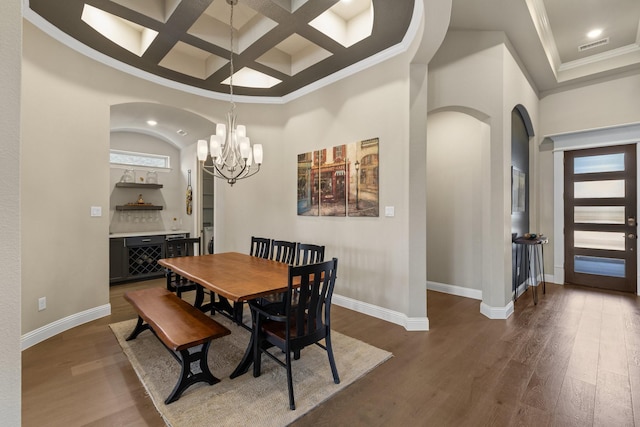 dining room with baseboards, arched walkways, coffered ceiling, and wood finished floors