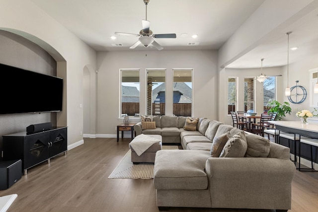 living area featuring ceiling fan, baseboards, and wood finished floors