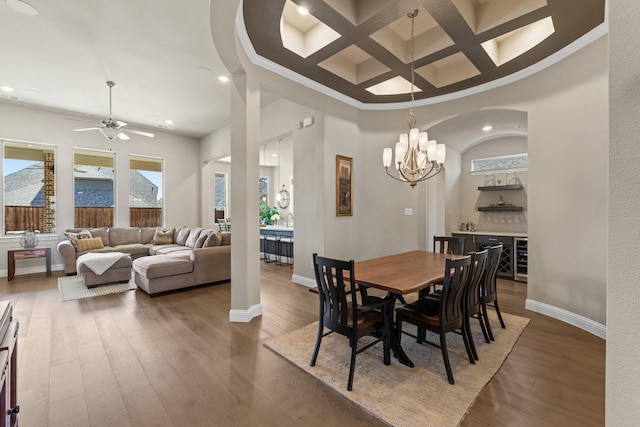 dining area with a dry bar, baseboards, coffered ceiling, hardwood / wood-style floors, and a high ceiling