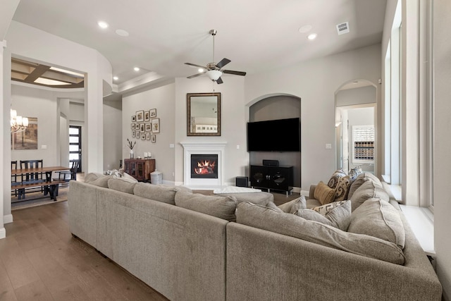 living area featuring a warm lit fireplace, wood finished floors, visible vents, and recessed lighting