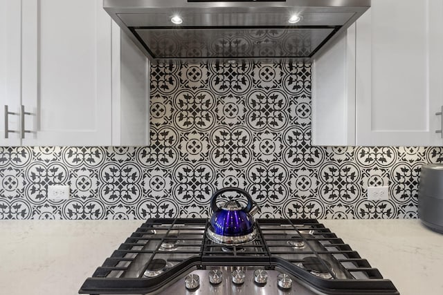 kitchen featuring stainless steel gas cooktop, white cabinets, and light stone counters