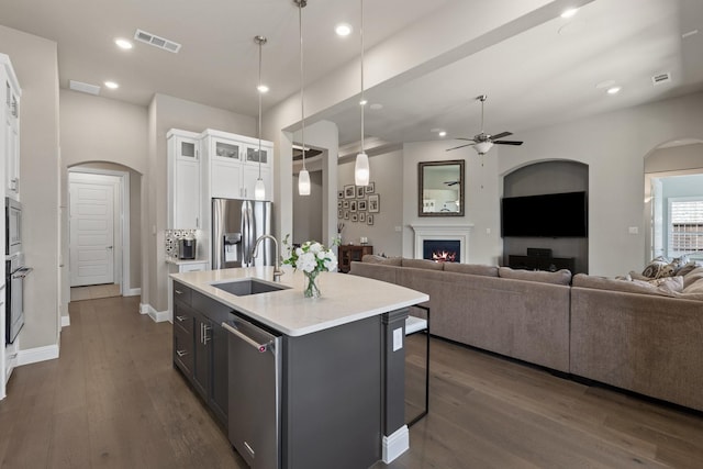 kitchen featuring stainless steel appliances, a sink, visible vents, white cabinets, and open floor plan