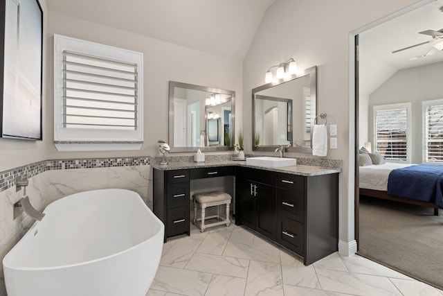 full bathroom with connected bathroom, a ceiling fan, vaulted ceiling, marble finish floor, and a soaking tub