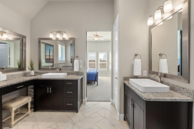 ensuite bathroom with vaulted ceiling, marble finish floor, and a sink