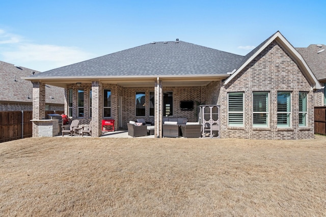 rear view of property featuring a shingled roof, fence, an outdoor hangout area, and brick siding