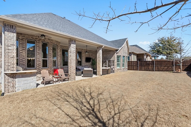 rear view of house featuring brick siding, a patio area, fence, and a ceiling fan