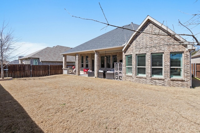 back of property featuring roof with shingles, fence, a patio, and brick siding