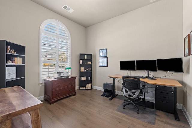 office with baseboards, visible vents, and wood finished floors