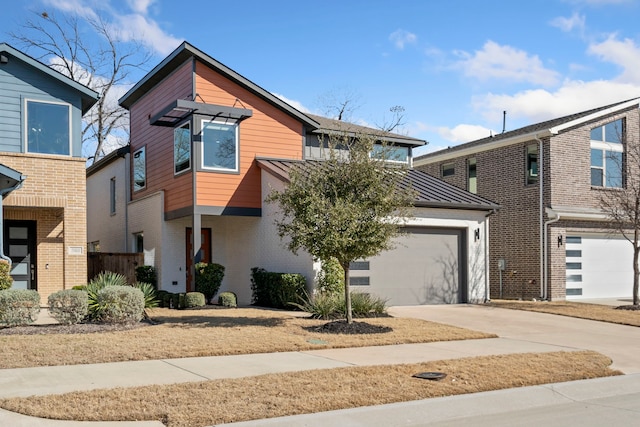 view of front of house featuring driveway, metal roof, an attached garage, a standing seam roof, and brick siding