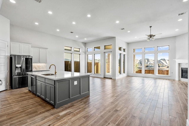 kitchen with visible vents, gray cabinets, stainless steel appliances, a glass covered fireplace, and open floor plan