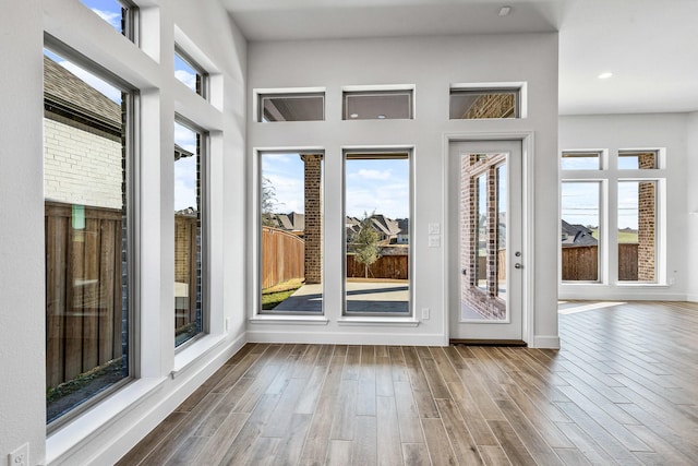 interior space with a high ceiling, plenty of natural light, wood finished floors, and baseboards