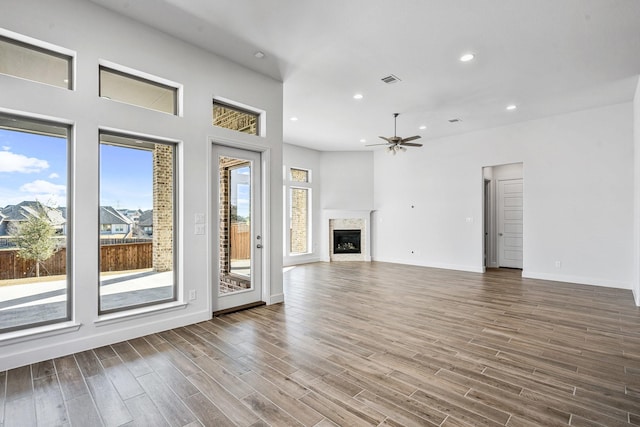 unfurnished living room featuring baseboards, ceiling fan, recessed lighting, wood finished floors, and a glass covered fireplace