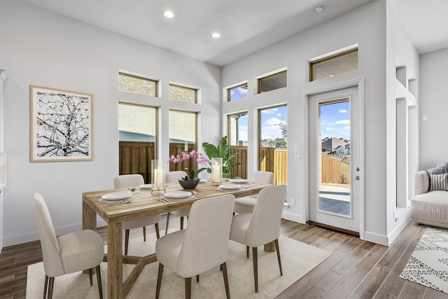 dining space featuring a towering ceiling, recessed lighting, baseboards, and wood finished floors