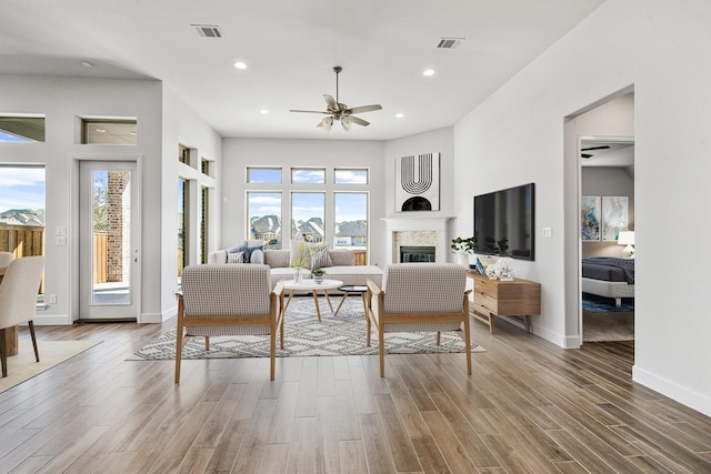 living room with a glass covered fireplace, wood finished floors, and recessed lighting