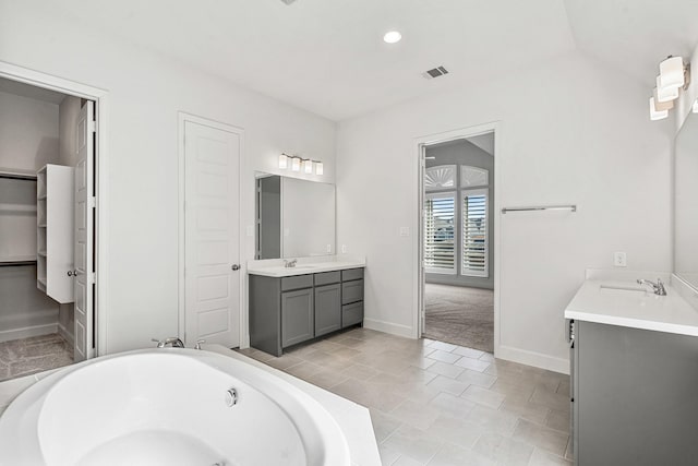 full bath with two vanities, a tub to relax in, visible vents, and a sink