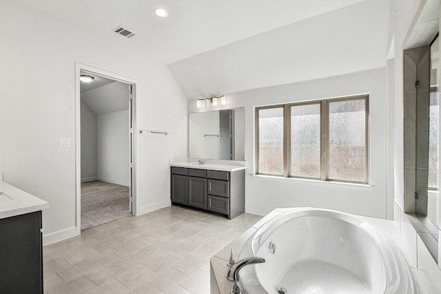 full bathroom with vanity, baseboards, visible vents, lofted ceiling, and a garden tub