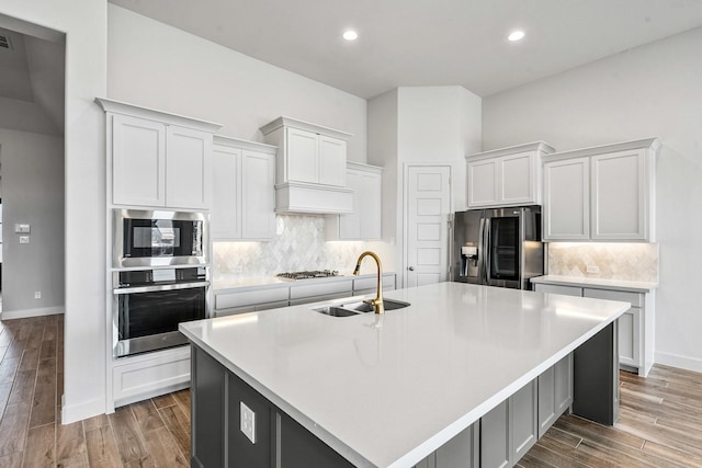 kitchen with a sink, stainless steel appliances, light wood-style floors, and light countertops