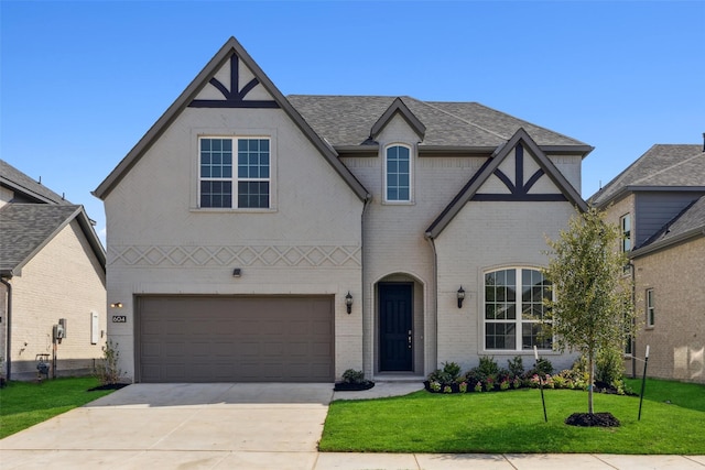 view of front facade with brick siding, a shingled roof, an attached garage, driveway, and a front lawn