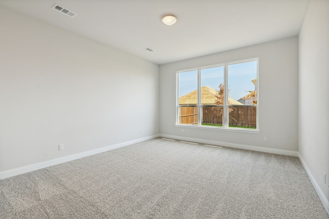 carpeted empty room featuring baseboards and visible vents