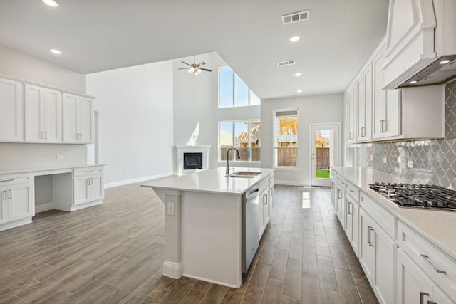 kitchen featuring a fireplace, a sink, visible vents, built in desk, and custom range hood