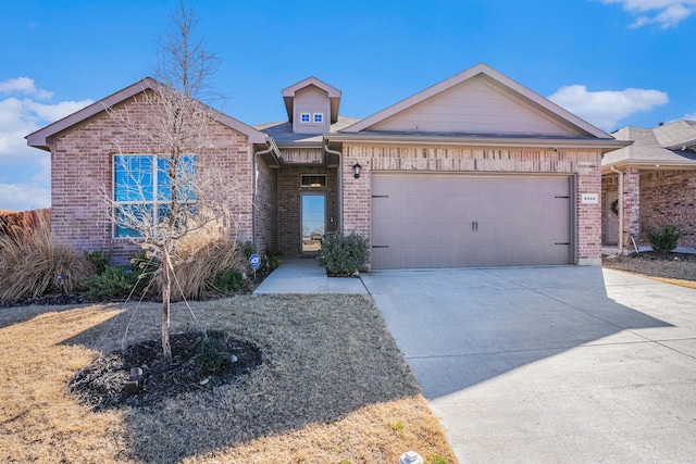 view of front of house featuring a garage, concrete driveway, and brick siding