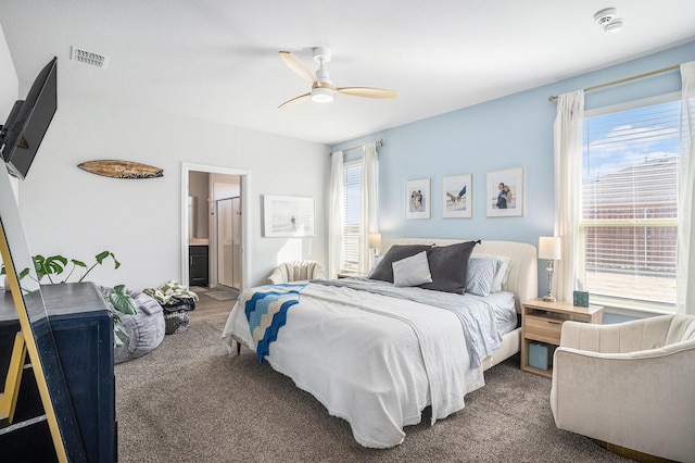 carpeted bedroom with connected bathroom, multiple windows, visible vents, and a ceiling fan