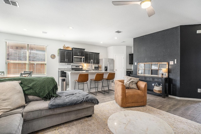 living room with light wood-style floors, baseboards, and visible vents