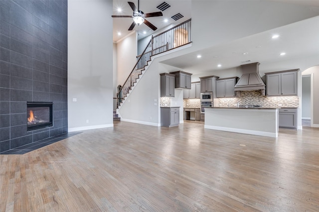 unfurnished living room with light wood finished floors, baseboards, visible vents, and a ceiling fan