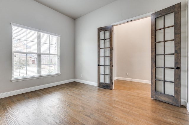 unfurnished room featuring french doors, light wood finished floors, and baseboards