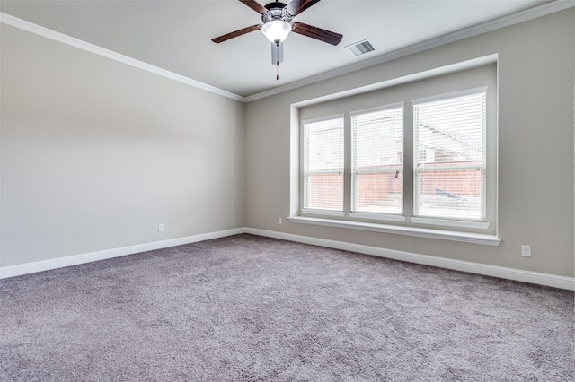 carpeted spare room with a ceiling fan, baseboards, visible vents, and crown molding