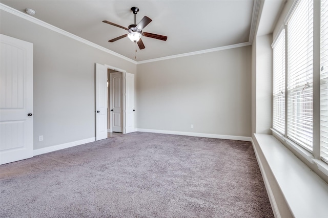 carpeted spare room with ornamental molding, a ceiling fan, and baseboards