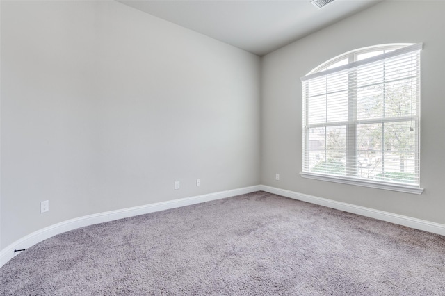 carpeted spare room with visible vents and baseboards